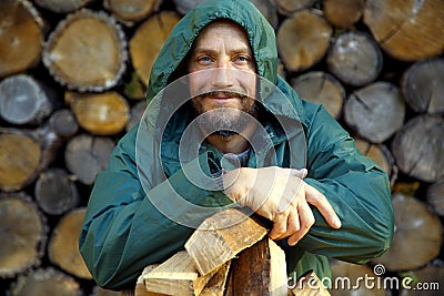 Portrait of a man with a bunch of chopped firewood. Bearded lumberjack with firewood for the fireplace. Stock Photo