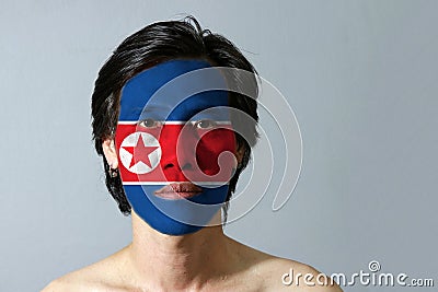 Portrait of a man with the flag of the North Korea painted on his face on black background. Stock Photo