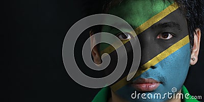 Portrait of a man with the flag of the Tanzania painted on his face on black background. Stock Photo