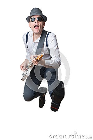 Man with hat plays electric guitar and jumps in the air Stock Photo