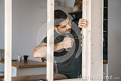 Portrait of a man in home clothes with a screwdriver in his hand fixes a wooden construction for a window in his house. Repair Stock Photo