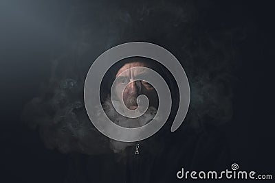 Man in hoodie with smoke in front of his face Stock Photo