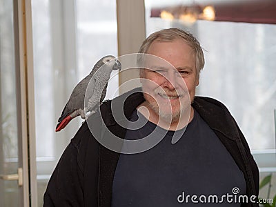 Man with a Jaco parrot on his shoulder Stock Photo