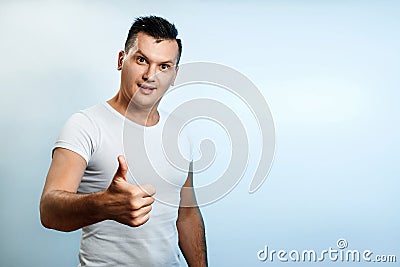 Portrait of a man on a light background, shows a thumbs up, puts a like. The concept of body language, human emotions, reaction Stock Photo