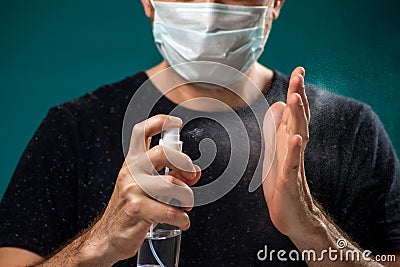 A portrait of man with medical face mask using disinfectant spray on hands. People, medicine, healthcare concept. Coronavirus Stock Photo