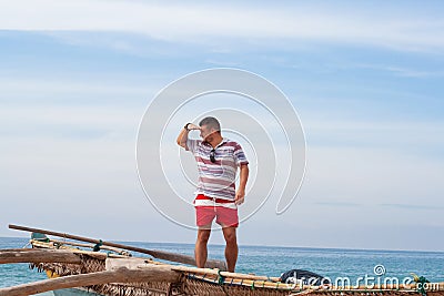 Portrait of a man with a middle beard in a shirt and red shorts on a traditional fisherman boat Stock Photo