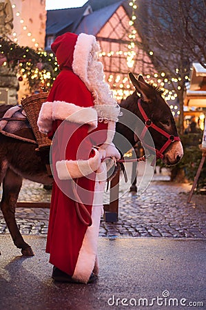 Portrait of man with santa claus costume and donkey at the christmas market Editorial Stock Photo