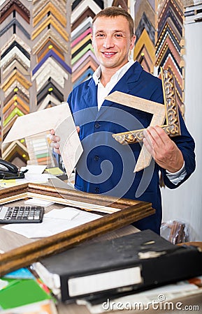 Portrait of man seller working with picture frames in atelier Stock Photo