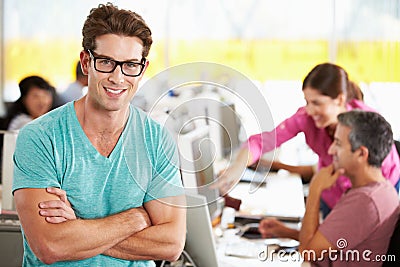 Portrait Of Man Standing In Busy Creative Office Stock Photo