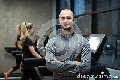 Portrait of man standing with women exercising on treadmills Stock Photo