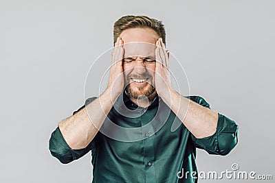 Portrait of man suffering huge headache or migraine grabbing head with both hands Stock Photo