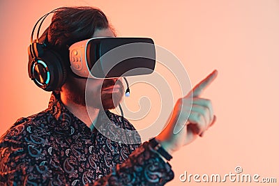 Portrait of a man with a vr headset and headphones touching the invisible touchscreen panel - virtual reality experience Stock Photo