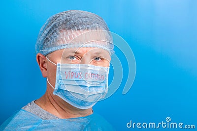 Portrait of man wearing medical uniform and mask with virus outbreak word at blue background. Protect your health. Coronavirus Stock Photo