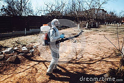 Portrait of male worker wearing protective clothing and spraying insecticide in fruit orchard Stock Photo