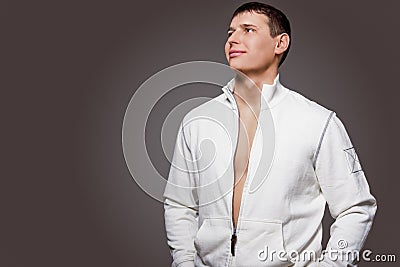 Portrait of Masculine Strong Tanned Caucasian Man in White Jacket. Posing Against Gray Studio Backdrop Stock Photo