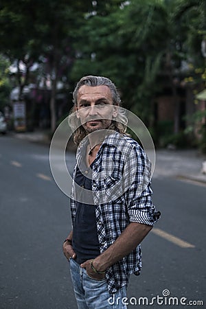 Portrait of mature handsome man in shirt and jeans walking on the street in asia Stock Photo