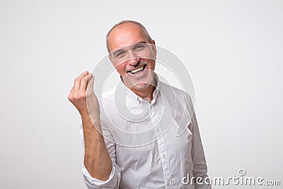 Portrait of mature handsome man in white shirt showing italian gesture Stock Photo