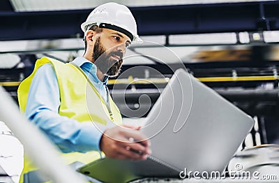 A portrait of an industrial man engineer with laptop in a factory, working. Stock Photo