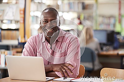 Portrait Of Mature Male Student Using Laptop In Library Stock Photo