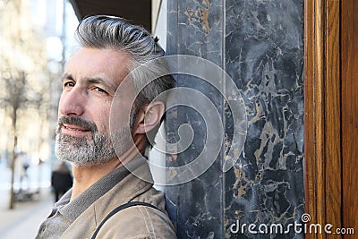 Portrait of mature man leaning on wall in town Stock Photo