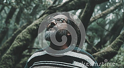 Portrait of mature man looking up with forest woods trees green ambient in background. Close up of male people in nature outdoors Stock Photo