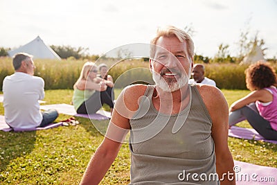 Portrait Of Mature Man On Outdoor Yoga Retreat With Friends And Campsite In Background Stock Photo