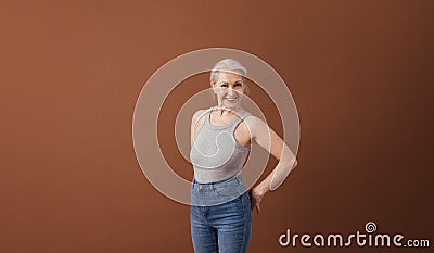 Portrait of a mature woman in casuals standing at brown background in studio Stock Photo