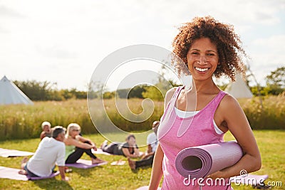 Portrait Of Mature Woman On Outdoor Yoga Retreat With Friends And Campsite In Background Stock Photo