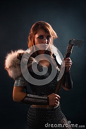 Portrait of a medieval, fantasy viking woman with an ax in her hands in the dark. Stock Photo