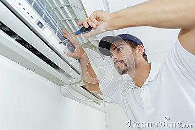 Portrait mid-adult male technician repairing air conditioner Stock Photo