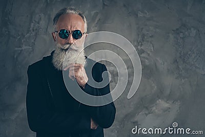 Portrait of minded harsh masculine man touching his chin looking wearing black raincoat isolated over gray background Stock Photo