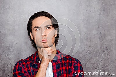 Portrait of minded young man looking up while standing near gray wall Stock Photo