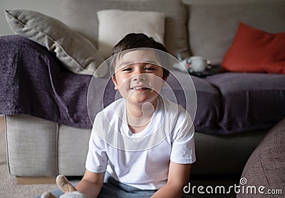 Portrait mixed race boy sitting on floor playing with toy with happy face, Cute boy looking at camera with smilibg face, Child Stock Photo