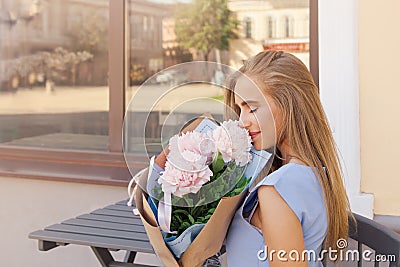 Portrait of modern fashion trendy women sitting in outdoor restaurant with Bouquet of peonies Stock Photo