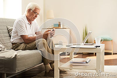 Senior Man Using Smartphone at Home Stock Photo