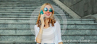 Portrait of modern young woman calling on smartphone sitting on the stairs on city street Stock Photo