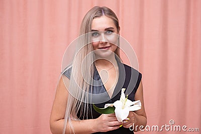 Portrait of the most beautiful girl with gorgeous smooth long hair with a flower in her hands on a pink background Stock Photo
