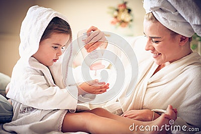 Portrait of mother and daughter after bath applying body lotion. Stock Photo