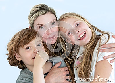 Portrait of a mother, with her children son 6 and daughter 11 in a jolly casual mood. The background is solid light blue Stock Photo