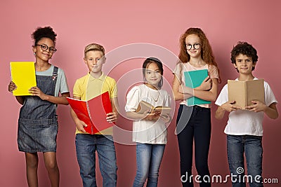 Portrait of multiethnic kids with textbooks and notebooks ready to start new school year over pink background Stock Photo