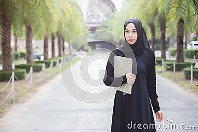 Portrait muslim woman in black hijab with laptop. Stock Photo