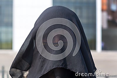 Portrait of a Muslim woman in national clothes covering her face in a European city Stock Photo