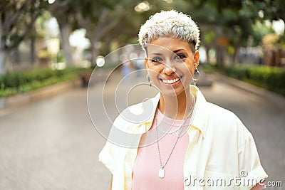 Portrait of natural millenial woman with short blonde hairstyle wearing silver jewelry, earrings and necklace, smiling and looking Stock Photo