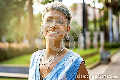 Portrait of natural millenial woman with short blonde hairstyle wearing silver jewelry, earrings and necklace, smiling and looking Stock Photo