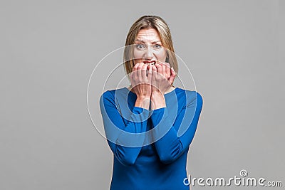 Portrait of nervous anxious woman biting her nails. indoor studio shot isolated on gray background Stock Photo