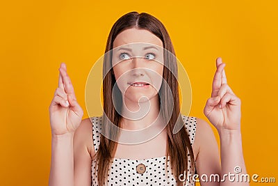 Portrait of nervous lady crossed fingers bite lip look side on yellow background Stock Photo