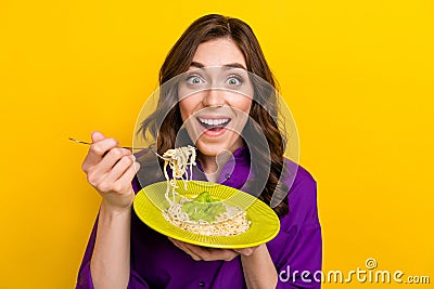 Portrait of nice overjoyed astonished girl hand hold noodles pasta fork plate isolated on yellow color background Stock Photo