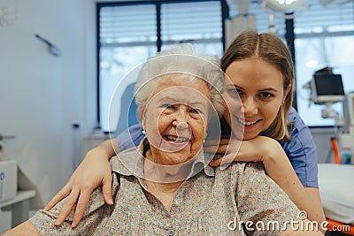 Portrait of nurse and senior patient talking in hospital corridor. Emotional support for elderly woman. Stock Photo