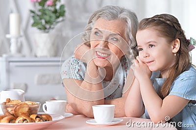 Portrait of old woman with a young girl drinking tea at home Stock Photo