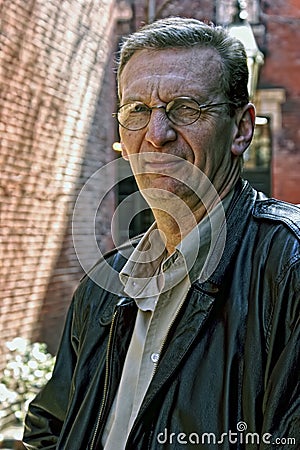 Portrait of older man squinting outdoors Stock Photo